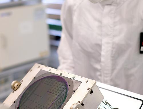 Una persona sostiene un equipo con una oblea procesada en la Sala Blanca de Micro y Nanofabricación