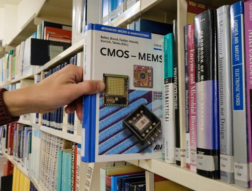 Estantería con libro destacado de CMOS-MEMS en la biblioteca del IMB-CNM