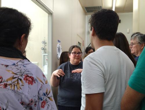 Andrea Azambuja delante de Grabados Húmedos con público de la visita a la Sala Blanca de Micro y Nanofabricación