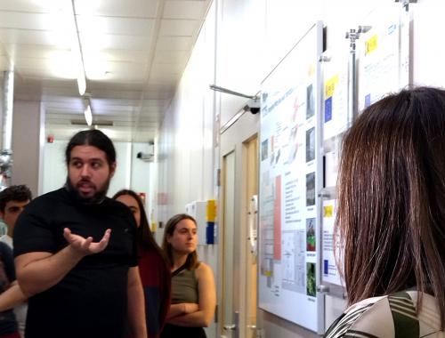 Olaf Vázquez delante del pasillo central de la Sala Blanca de Micro y Nanofabricación con público de la visita