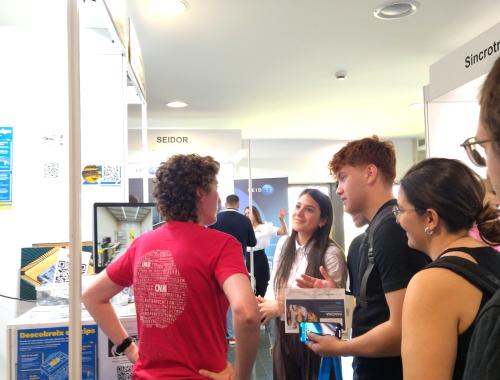 Marta Fernández replying questions at the IMB-CNM Stand at MEMEnginy 2025 UAB