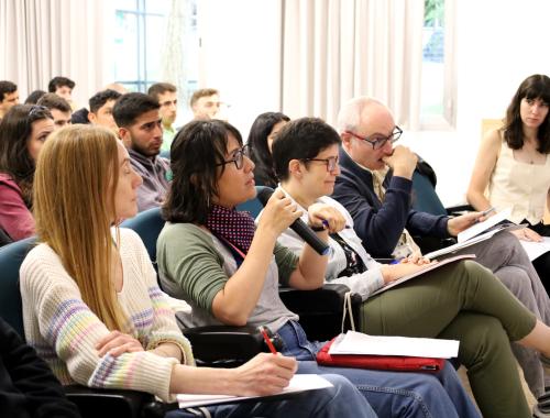 Stella Vallejos with the microphone as a member of the jury in the first row of the Young Researchers Day 2025