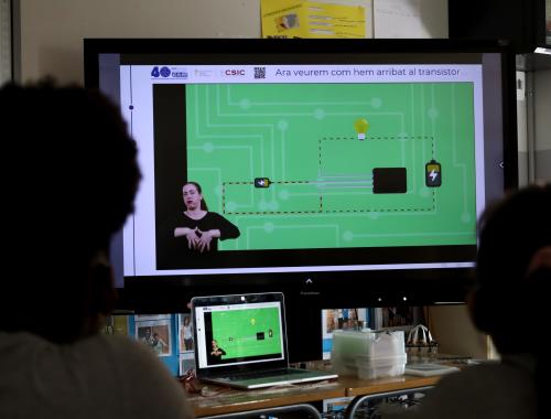 Dues nenes miren el vídeo del transistor amb adaptació a LSC a l'aula de classe