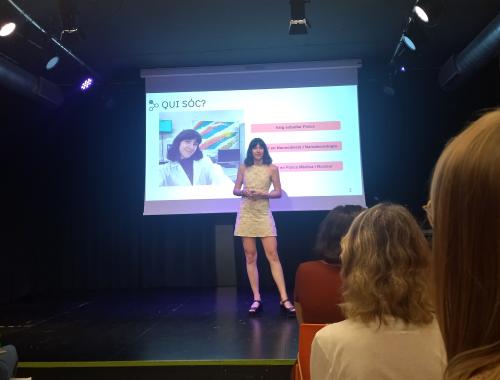 Xerrada de Carla Riera Llobet a Vil·la Urània per la Nit de la Recerca, sobre l'escenari amb la presentació al fons