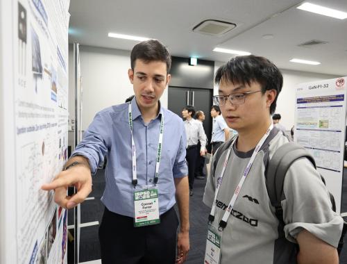 Conrad Ferrer showing his poster to a person at the ISPSD in Japan 2025