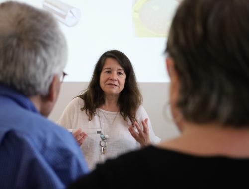 científica haciendo divulgación sobre microelectrónica a personas jubiladas