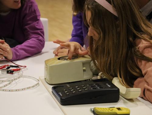 Niña jugando con teléfono antiguo en taller de divulgación