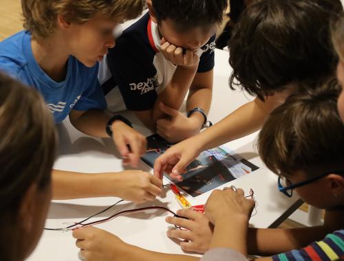 Varios niños alrededor de un circuito electrónico en taller de divulgación