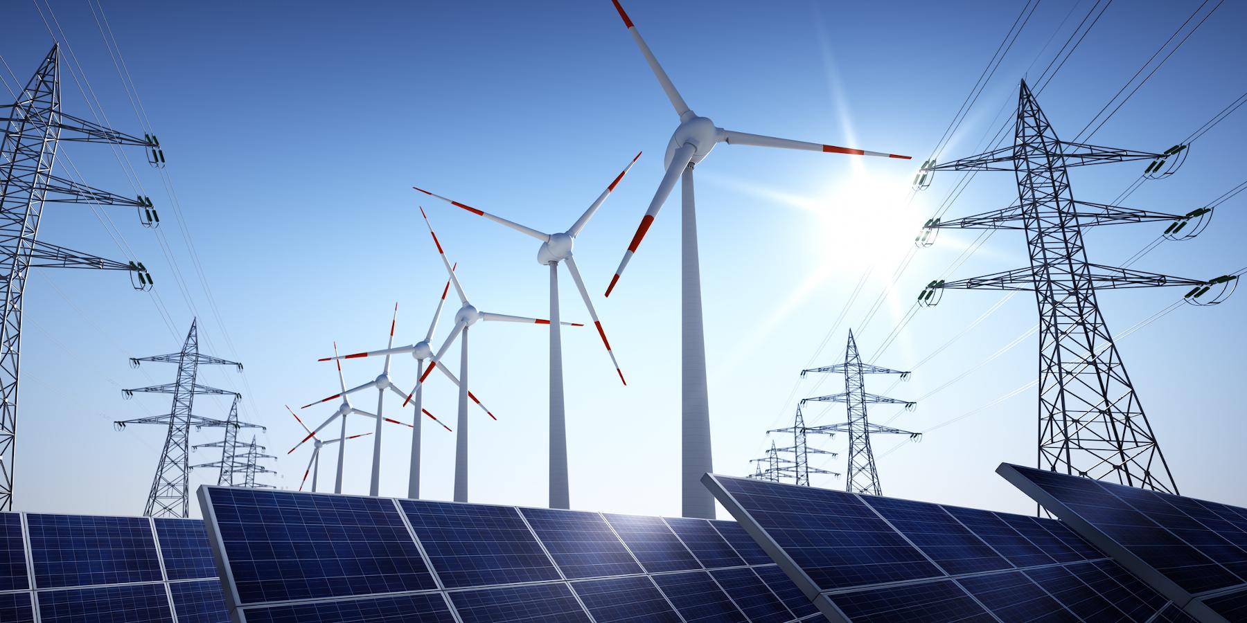 Montaje de paneles solares, palas eólicas y red eléctrica sobre cielo azul y despejado. iStock