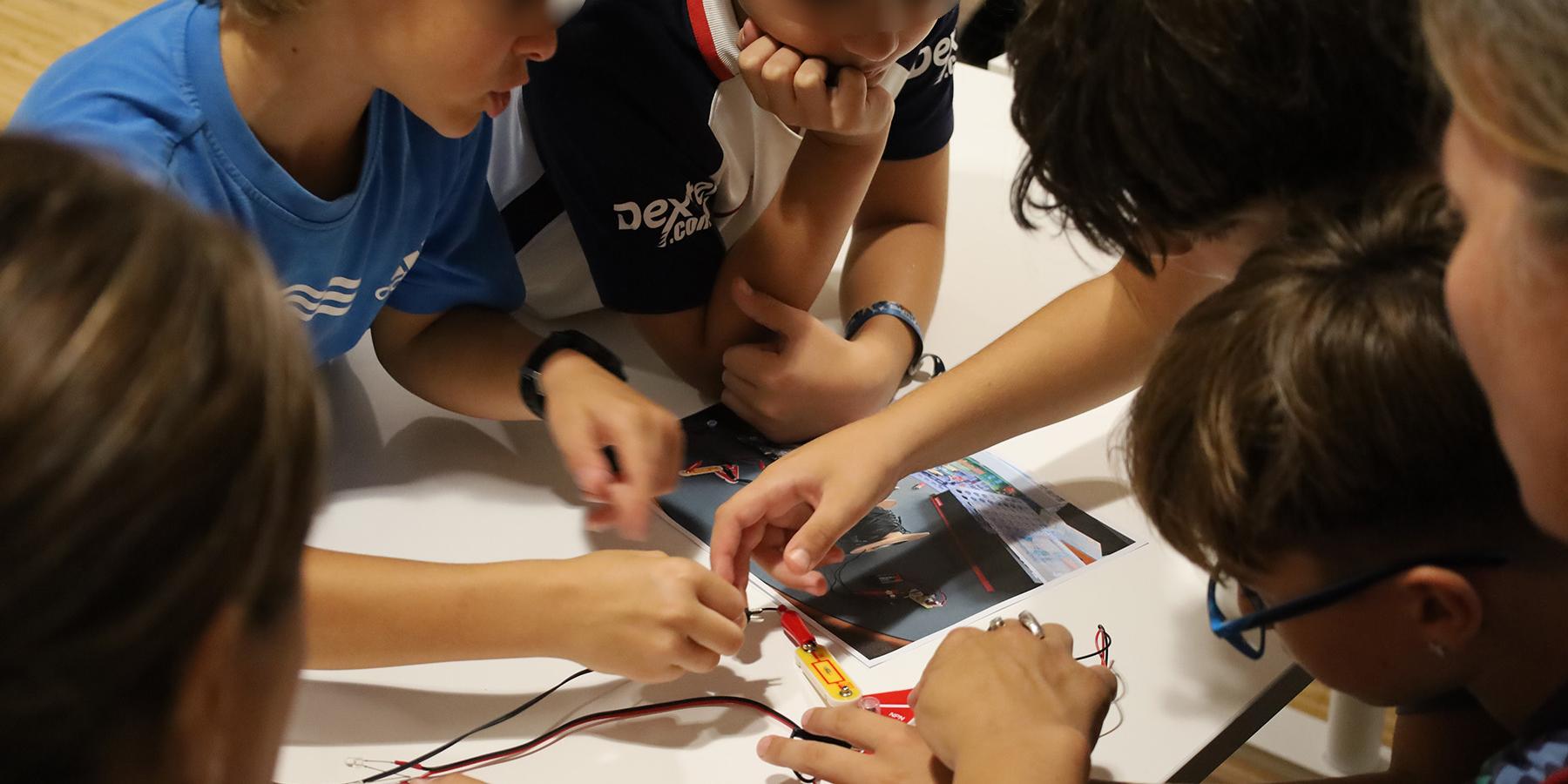 Varios niños alrededor de un circuito electrónico en taller de divulgación