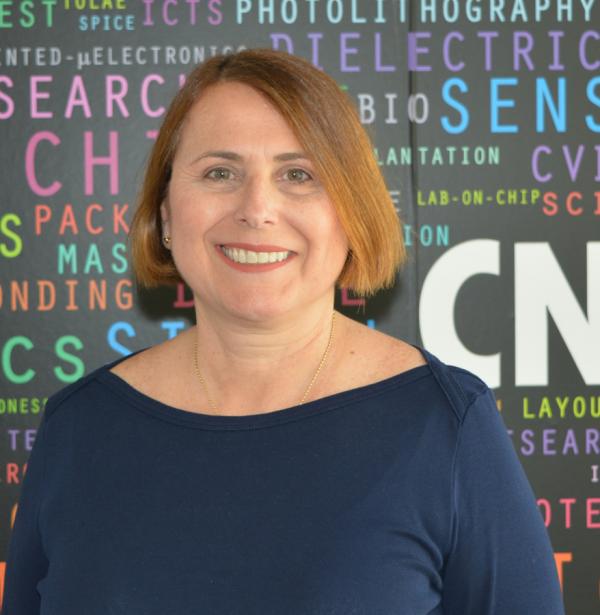 La nueva gerente del IMB-CNM Mari Carmen Porto sobre fondo negro con letras de colores en el IMB-CNM