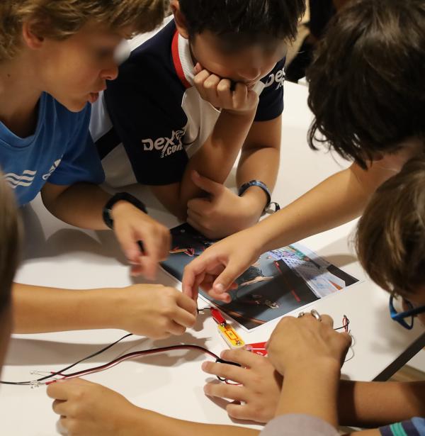 Varios niños alrededor de un circuito electrónico en taller de divulgación